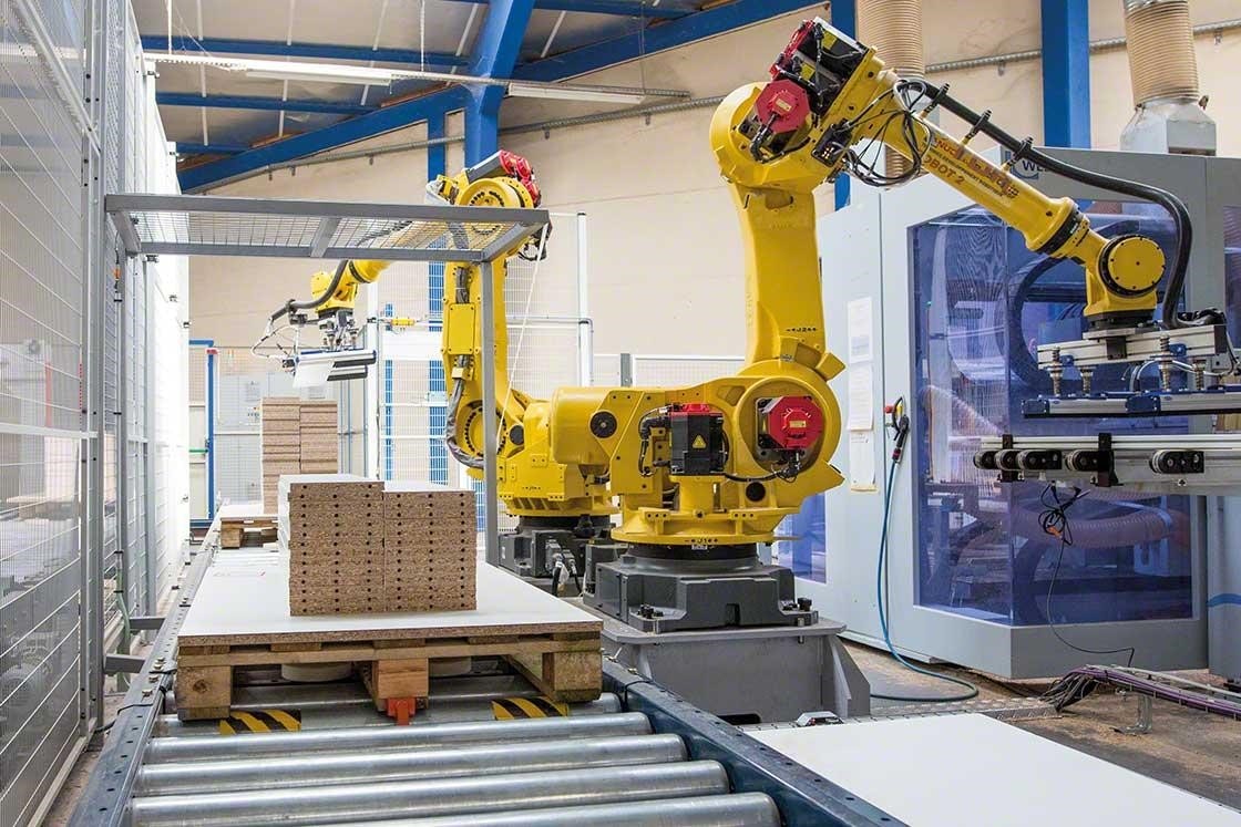 Des bras mécanisés qui réalisent la palettisation des marchandises dans un entrepôt robotisé.