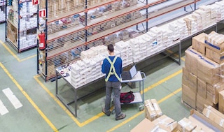 Un employé vérifie la conformité des produits d’un entrepôt à l’aide d’un ordinateur portable
